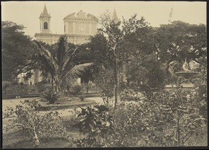 View of city park with fountain; bell tower and façade of Cathedral of San José in distance