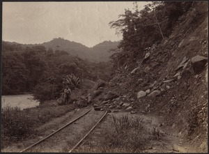 Men clearing a rockslide off of railroad tracks; river to left
