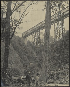 Two men standing near tall steel railroad bridge