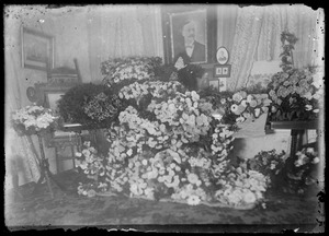 Coffin in home with flowers. Portrait on wall