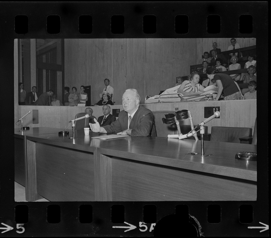 Former Boston John F. Collins addresses City Council hearing on the plight of handicapped persons as Helene Cummings watches from her stretcher-bed