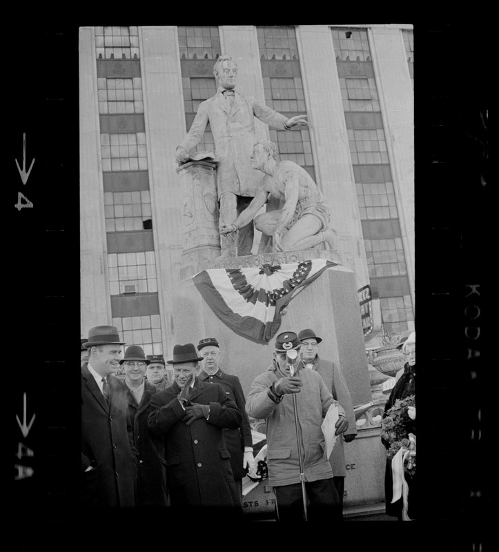 Group of people in front of the Emancipation Memorial, Park Square, Boston, including Governor Volpe, standing next to the speaker