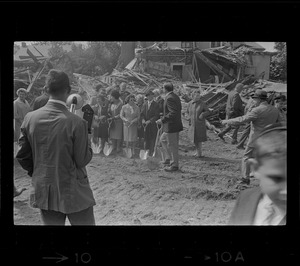 Crowd of people standing in front of destroyed building and holding shovels
