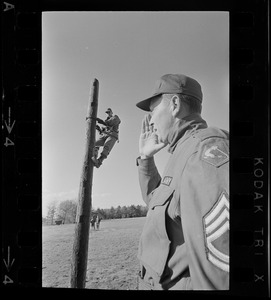 US Army solider on top of pole, and another soldier shouting with hand to face in foreground during blackout in Boston