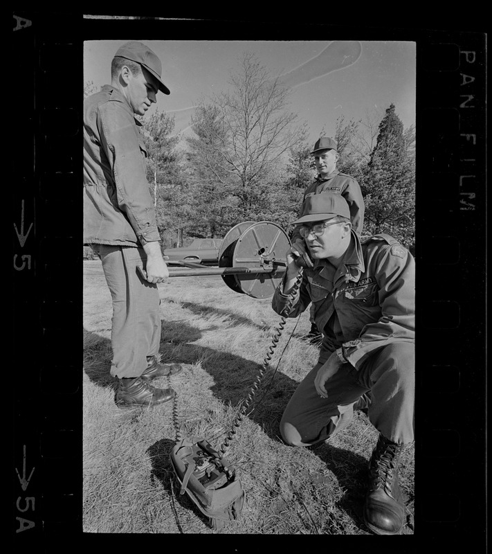 Three men laying wires while one talks on portable communication device during blackout in Boston