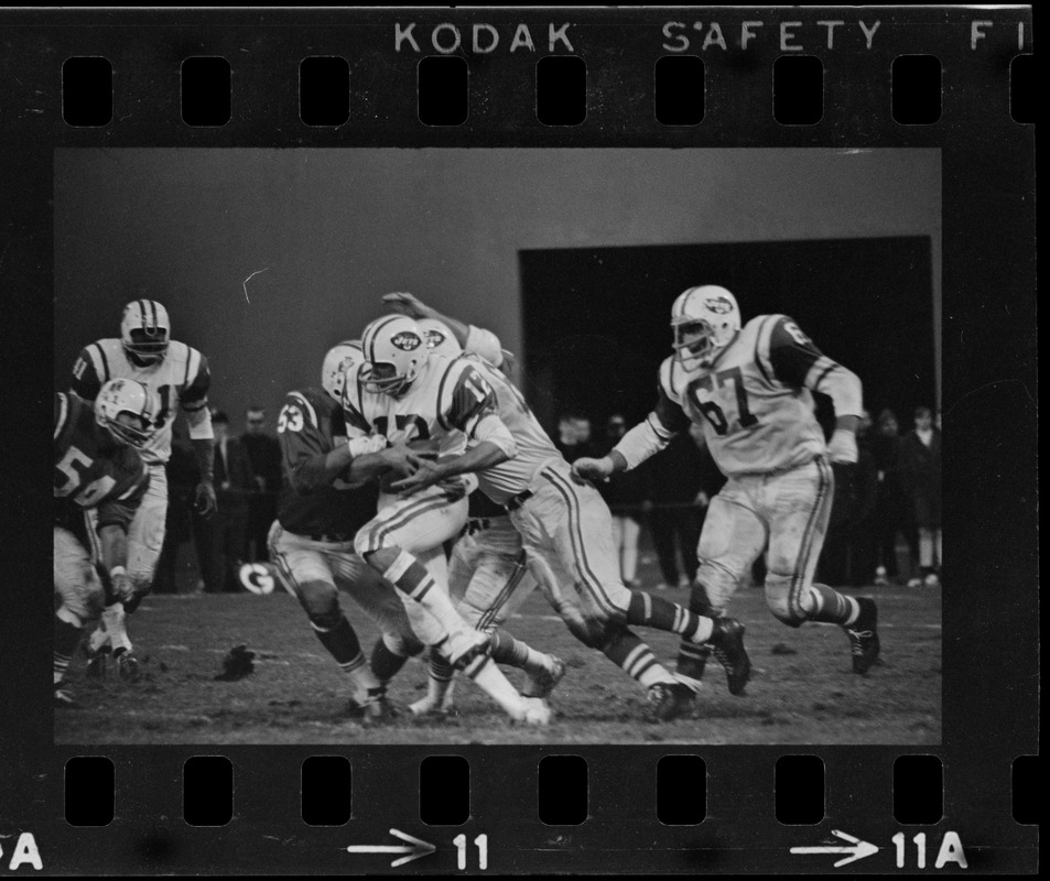 New England Patriot tackling a New York Jet player in a football game