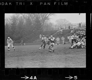 Football player with possession of the ball being approached by the defense