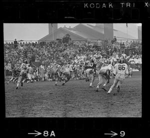 Football game and spectators in bleachers in rain