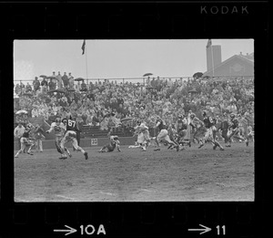 Football game and spectators in bleachers in rain