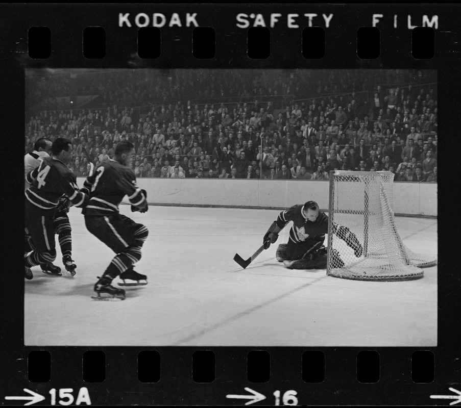 Toronto Maple Leafs goalie, Johnny Bower (no. 1), reaching for puck after goal is made in game against the Boston Bruins