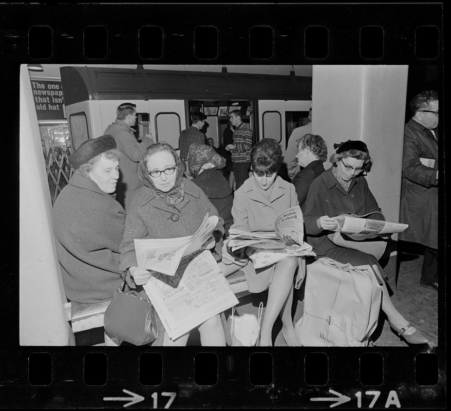 Row of ladies reading newspaper at train station, Boston blackout