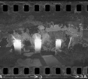 Man sitting at table talking and reading by candlelight during Boston blackout