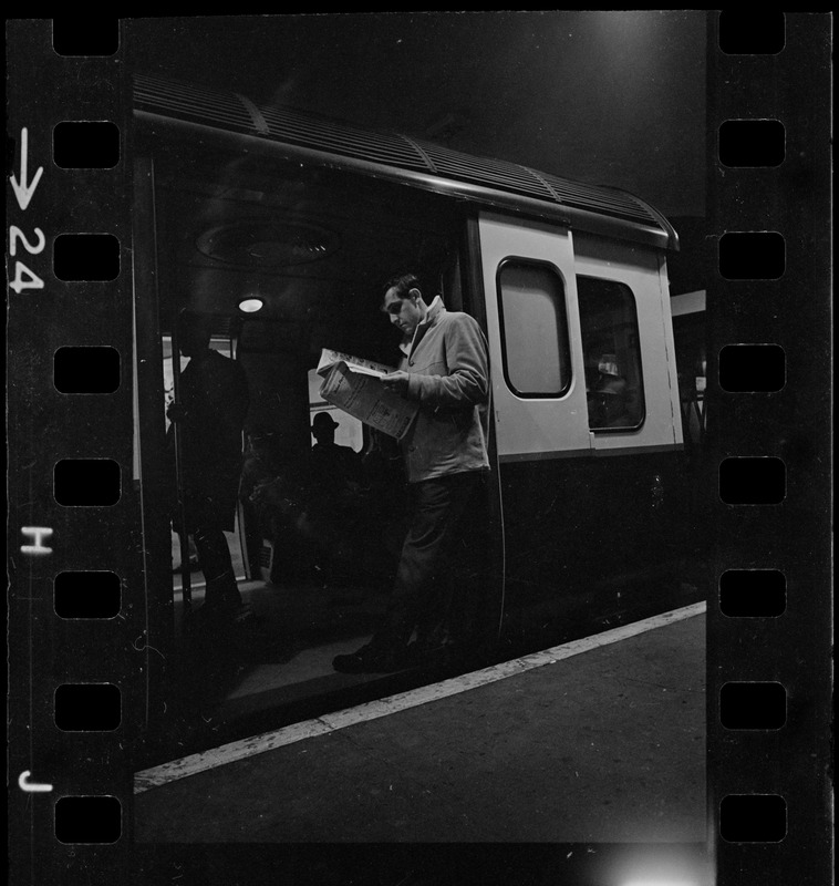 Man standing in train car doorway and darkened platform during Boston blackout