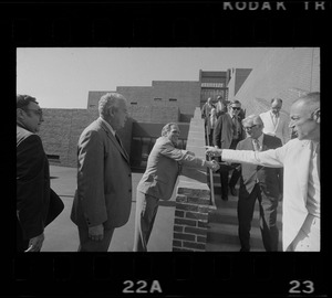 Boston Mayor Kevin White talking with group of men on stairs while on tour of new school