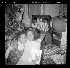 Two girls pose in front of dolls and a Christmas tree