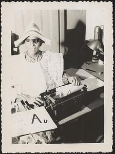 Jack Miller sits at typewriter wearing costume made of newspaper