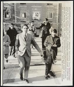 Brandeis University Pres. Morris Abram walks to his office with his son Joshua, 5, as suspended black students who took over the University's cummunications building (background) proposed another meeting with the school administration (1/12). The black students are protesting " Racist Policies" of the school.