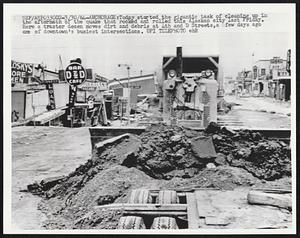 Today started the gigantic task of cleaning up in the aftermath of the quake that rocked and rolled this Alaskan city last Friday. Here a tractor dozen moves dirt and debris at 4h and D Streets, a few days ago ons of downtown's busiest intersections.