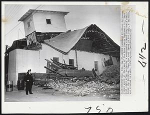 Where Salesman Killed--A Policeman stands guard at the rear of the Kern County Equipment Co., here last night after yesterday's earthquake almost completely demolished the building. When the roof caved in Pat Cosby, a salesman, was crushed to death.