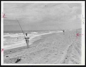 Fishing in Solitude. A surf fishermen pulls one in on Hatteras Island, while his companion waits for a strike. This stretch of beach is within the Cape Hatteras National Seashore Recreation Area. Commercialism is tightly restricted and it's possible to fish in absolute solitude.