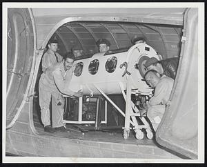 Mercy Flight - Air National Guard pilots Lt. Dante Memmolo (left) and Capt. Lionel Veilleux (right) helping police and other Guardsmen load a 600-pound iron lung aboard National Guard plane yesterday for flight to Lewiston, Me. Lung was needed for seven-year-old boy stricken with polio.