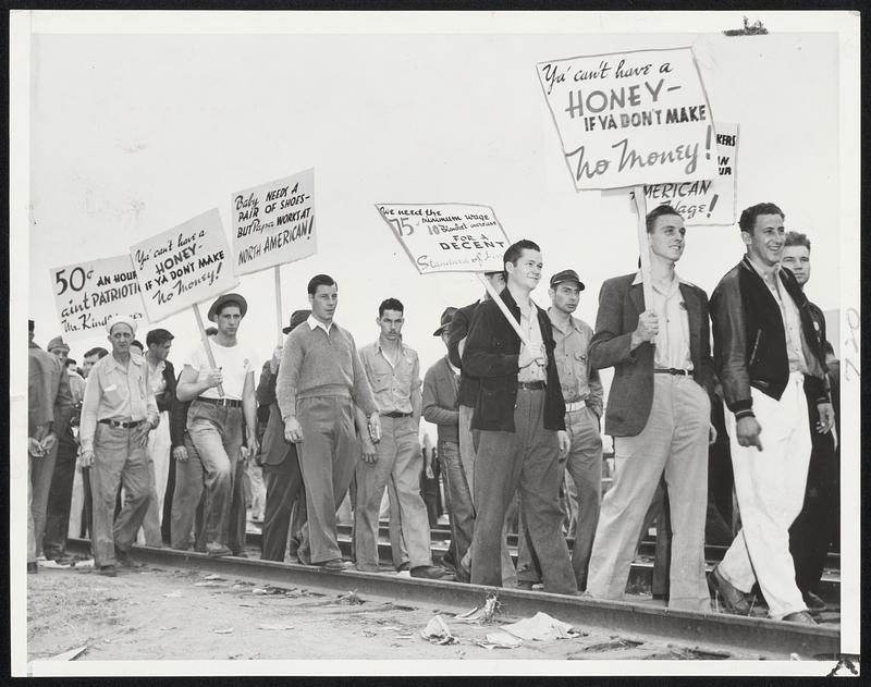 Lighthearted Strikers are shown marching in a picket line around the North American Aviation plant at Inglewood, Calif. Defense work halted when 9000 CIO workers struck. Unless men resume work, President Roosevelt will order the army to take over the plant tomorrow.