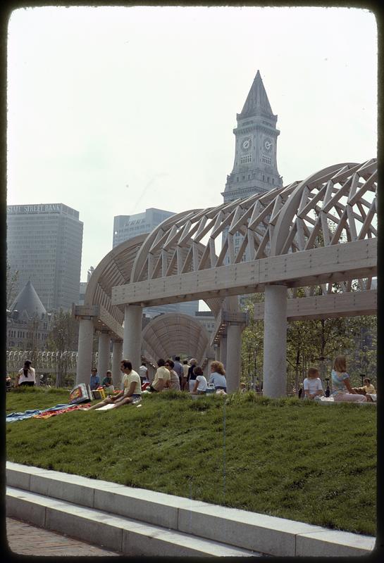 People sitting on grass, Christopher Columbus Park, Custom House Tower in background