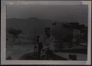 Young man sitting on a fence in a park or playground