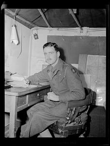 Man in uniform posing at desk with pen