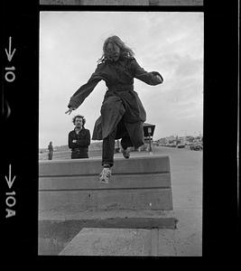 Person wearing trench coat jumping from wall