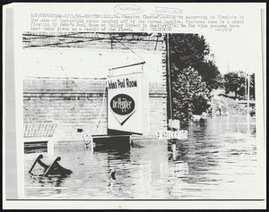 Weather Hurricane. Scottsville, VA.: Massive flash flooding is occurring in Virginia in the wake of torrential rains touched off by the former Camille. Pictured here is a chair floating by John’s Pool Room on Valley Street in Scottsville. So far nine persons have lost their lives as a result of the flood.