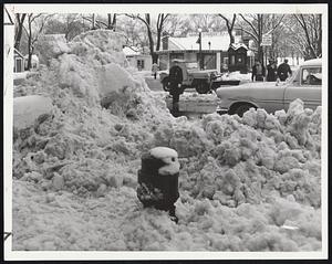 Plow left this huge pile of snow on Tremont St., but trucks later carted it away. At right, early riser splashes through deep puddle created by rising temperatures at Beacon and Charles streets. Armies of shovelers have now cleared downtown area.