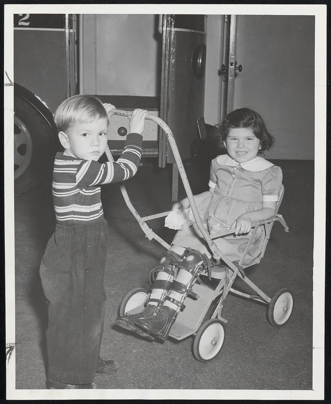 Gallantry to a young lady with a brace on both legs is appreciated by Barbara Thompson, 5, of Ft. Banks, Winthrop, who is given a helping hand by her three-year-old brother, Kenneth.