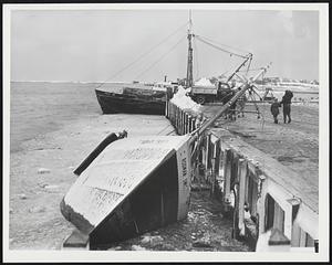 In Storm's Aftermath, the shore line at Scituate Harbor was littered with wrecked boats, such as one seen here, and a mass of debris of all kinds.