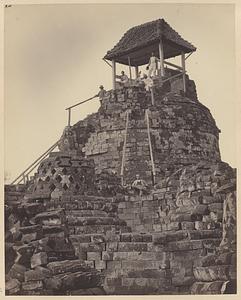 Europese mannen poseren op het tempelcomplex van de Borobudur bij de bovenste stupa waarop een afdak en trapleuningen zijn geplaatst
