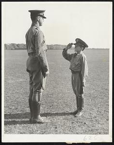 The little man on the right is attending the La Salle Military Academy and, according to his family traits, should major in equestrianism. For he is Alfred Sande, 13 years old, the adopted son of Earl Sande, the famous jockey of other years. Furthermore, he is the son of the late Clarence Kummer, another famous jockey, whose widow Sande married. The youngster is saluting Cadet Officer Joseph Smolik.