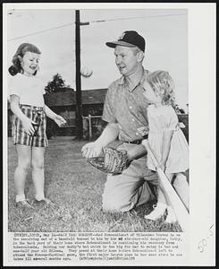 Back Yard Workout -- Red Schoendienst of Milwaukee Braves is on the receiving end of a baseball tossed to him by his six-year-old daughter, Cathy, in the back yard of their home where Schoendienst is continuing his recovery from tuberculosis. Holding her daddy's bat which is too big for her to swing is two and one-half year Eileen. They posed at their home before Schoendienst left to attend the Braves-Cardinal game, the first major league game he has seen since he was taken ill several months ago.