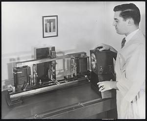 In a magnetic fatigue testing machine at U. S. Steel's Research and Development Laboratory in the Oakland District of Pittsburgh, Pennsylvania, a steel sample is subjected to controlled vibration to determine its resistance to fatigue failure. Vibrating at about 100 cycles per second, the ends of the sample appear blurred in the photograph. The laboratory technician is about to use a stroboscopic light. In this light the sample appears to be bending slowly and its surfaces can be examined for small cracks.