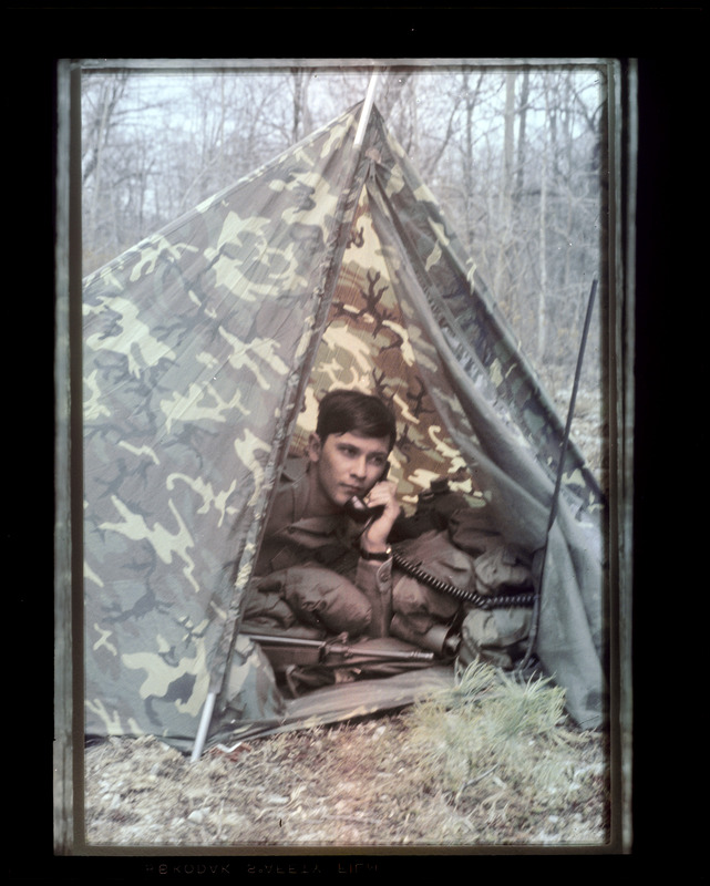 Man in camouflage tent talking on radio