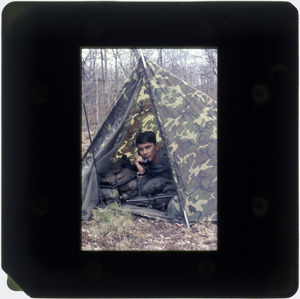 Man in camouflage tent talking on radio