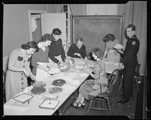 Servicemen decorating cake with group of women