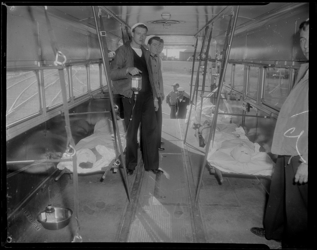 Military personnel aboard a bus filled with injured persons lying on cots, likely military personnel injured in the U.S.S. Bennington aircraft carrier explosion off coast of Rhode Island