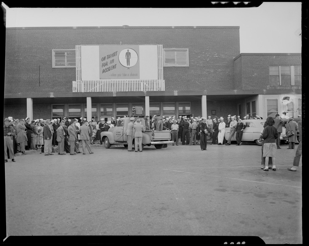 U.S.S. Bennington aircraft carrier explodes off coast of Rhode Island. Military personnel standing in a parking lot in front of a building