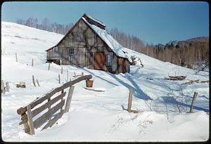 Barn and fence on snow-covered hill