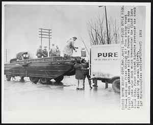 Flood Style Pickup--a milk can flies through air from pickup truck (right) which gathered milk from farmers still on dry land, into Army duck which transported the fluid into Sioux City. Flood blocked highways prevented the truck from making its usual delivery.