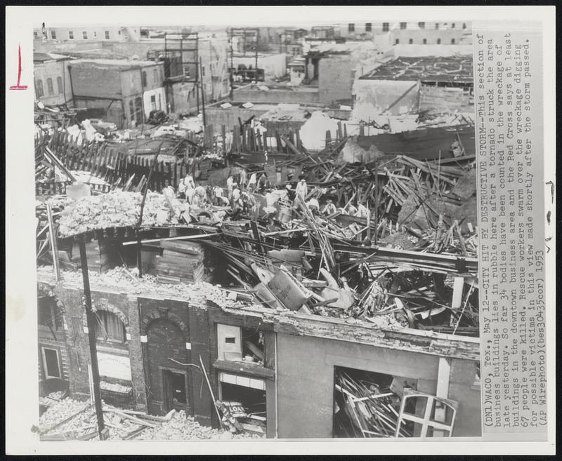 City Hit by Destructive Storm--This section of business buildings lies in rubble here after a tornado struck the area late yesterday. So far 34 bodies have been counted in the wreckage of buildings in the downtown business are and the Red Cross says at least 67 people were killed. Rescue workers swarm over the wreckage digging for possible victims in this view made shortly after the storm passed.