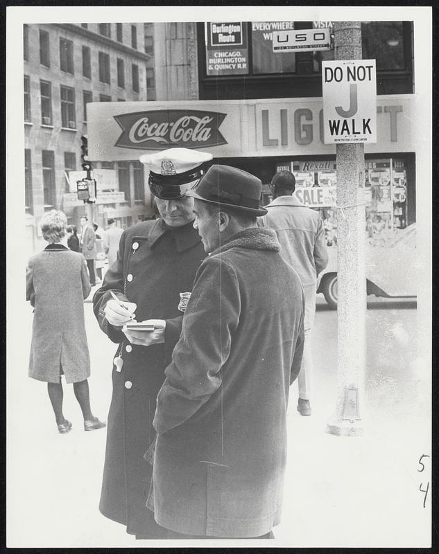 Jaywalker gets the bad news as traffic officer writes out ticket which will mean a $1 fine for offender who crossed against the "Walk-Don't Walk" lights at Tremont and Boylston streets. The new anti-jaywalk law went into effect April 1.