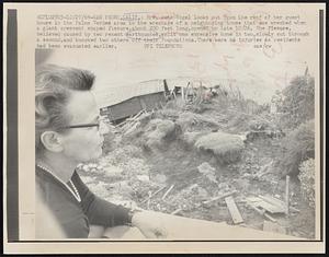 Mrs. Auto Vogel looks out from the roof of her guest house in the Palos Verdes area to the wreckage of a neighboring house that was wrecked when a giant crescent shaped fissure, about 200 feet long, opened up late 10/26. The fissure, believed caused by two recent earthquakes, split one expensive home in two, slowly cut through a second, and knocked two others off their foundations. There were no injuries as residents had been evacuated earlier.