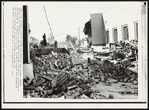 Quake Did This -- A skip loader clears debris in San Fernando, a Los Angeles suburb, following yesterday's earthquake in Southern California. Property damage was extensive as walls collapsed, streets buckled and caved in.