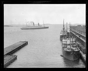Ships including "Vela" docked in foreground, unidentified ocean liner in background